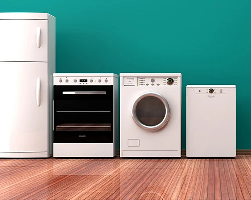 A refrigerator, oven, washing machine and dishwasher on a wooden floor against a green wall