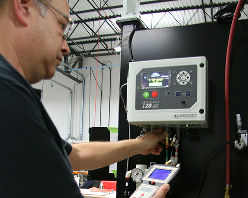 Man using a hand-held calibration instrument attached to a CTS leak test unit in a factory