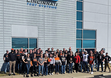 A group of CTS employees wearing Cincinnati Bengals attire standing in front of the CTS building.