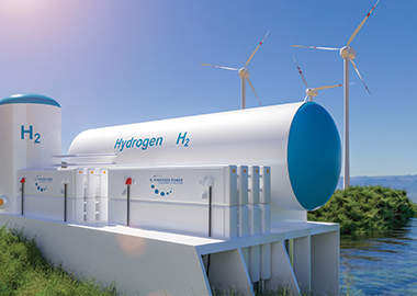 Image shows hydrogen storage tank, wind turbines and solar panels on the edge of a lake.