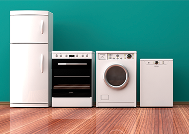 A refrigerator, oven, washing machine and dishwasher on a wooden floor against a green wall