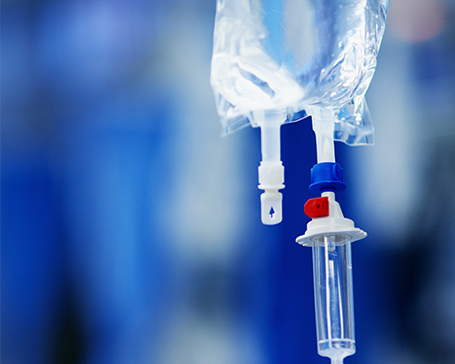 Image shows hanging IV bag with a clear liquid connected to a drip chamber.
