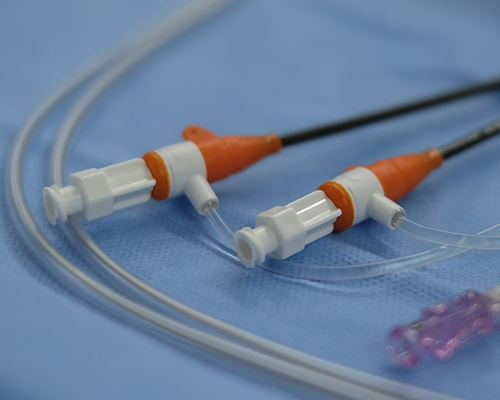 Image shows two introducer sheaths side by side on a blue medical fabric, with tubing curving in front of them.